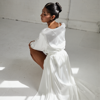Bride crouching down while satin maxi robe drapes behind her