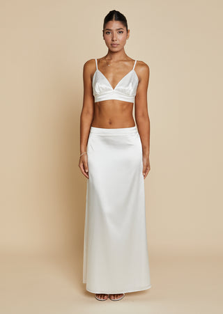 Front view of bride wearing white satin bralette and maxi skirt 