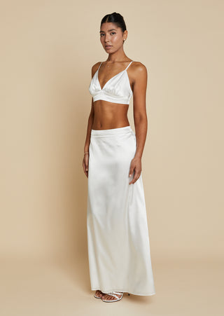 Quarter front view of bride wearing white satin bralette and maxi skirt 