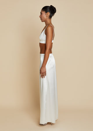 Side view of bride wearing white satin bralette and maxi skirt 