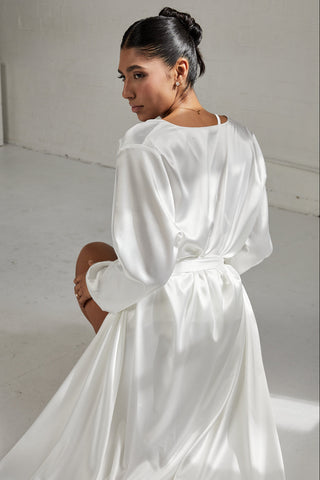 Woman wearing a white satin robe in a minimalistic setting